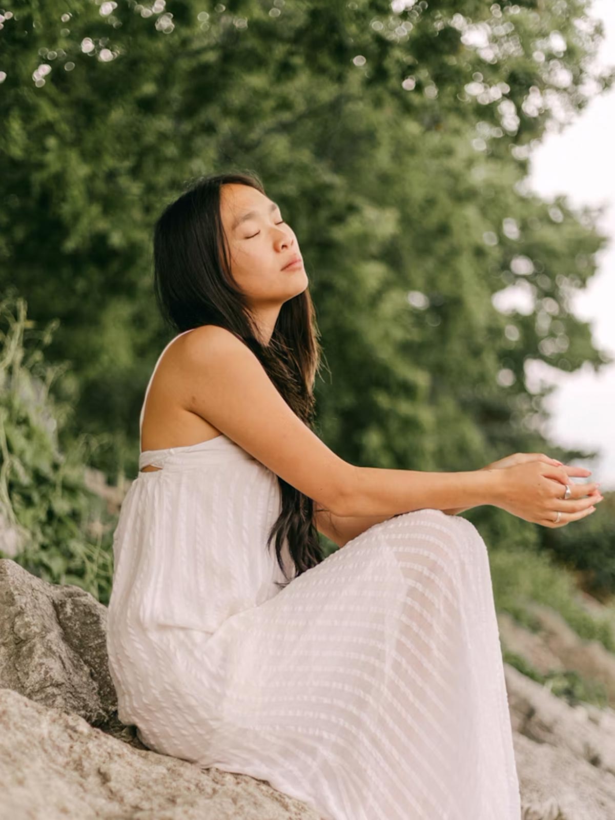 Frau sitzt entspannt im Grünen und genießt einen Moment der Ruhe