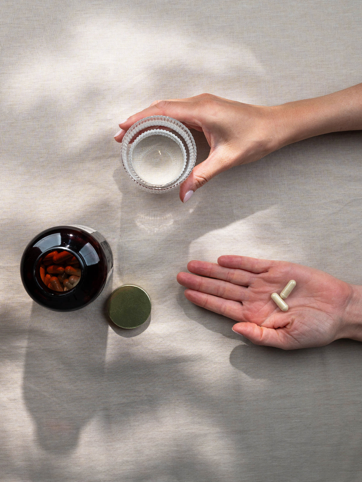 Kurkraft Bio Ashwagandha Kapseln – Einnahmeszene mit Glas Wasser und Hand, die zwei Kapseln hält.