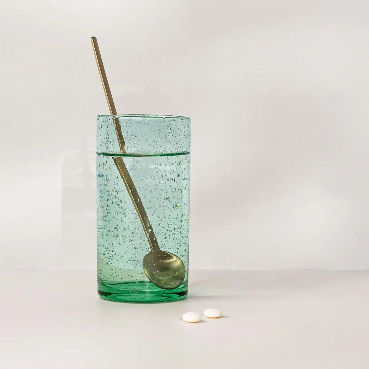 Vier MSM Tabletten neben einem Glas Wasser auf hellem Hintergrund