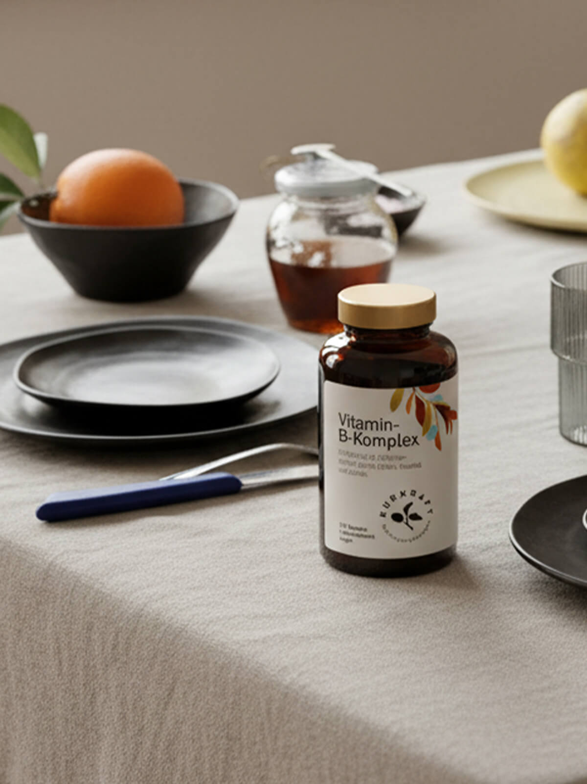 Kurkraft Vitamin B Komplex auf gedecktem Frühstückstisch mit Obst und Honig im Hintergrund
